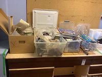 Overall view of containers and boxes holding sewing and crafting supplies including books, threads, and tools on table.