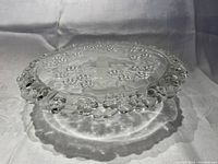 Side view showing the clear glass floral edge details and frosted central area of the pie/cake plate.