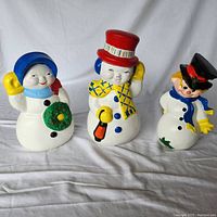 Front view of three ceramic Christmas snowman characters showing full figures and colors