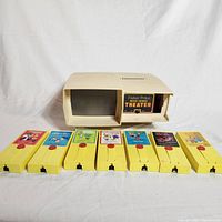 Full view of the Fisher Price Movie Viewer Theater device with 7 yellow plastic movie reels laid in front.