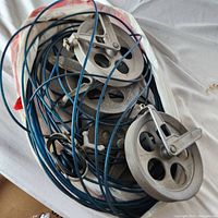 Photo of multiple metal pulley wheels with blue coated cables resting on a white surface.