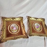 Wide shot of two matching framed art pieces showing the overall presentation, gold ornate frames, brown velvet mats, and oval central images.