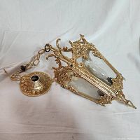 Full view of the hanging chandelier light showing gold-tone ornamental metal frame, chain, ceiling mount, and clear glass panels with star etching.