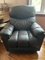 Front view of the dark brown leather recliner chair showing padded cushions and armrests.