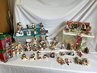 Full view of snowmen and Santa decorations arranged on plastic bins and a blue shelf. Includes standing figurines, hanging ornaments, and boxes.