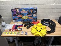 Photo of all components laid out on table showing track pieces, central intersection, decals, instructions, and cars