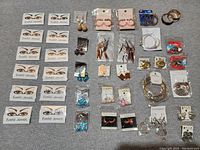 Top-down shot of large lot of assorted jewelry laid out on fabric surface, showing various earrings and bracelets.
