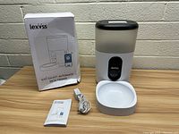 Lexvss Wifi Smart Automatic Pet Feeder with box, manual, USB cable, and feeding bowl on a surface.