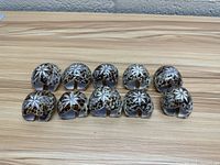 Front view of 10 carved sea shell napkin rings showing star and floral carved patterns and natural shell coloration.