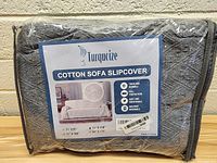 Front view of packaged Turquoize cotton sofa slipcover with brand label and product benefits visible showing softness, breathability, and size options.
