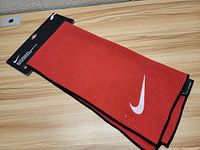 Red Nike golf towel laid flat showing full length and swoosh logo corner.