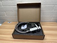 Chrome waterfall bathroom faucet packaged in foam inside a box, showing the faucet body and flexible hoses alongside an instruction manual.