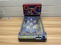 Full view of the vintage electronic pinball machine on a wooden table, featuring the playfield and top control panel with score display and lights.