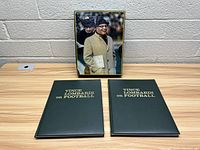 Two vintage hardcover books 'Vince Lombardi on Football' with black covers and gold title, and a box with a photo of Vince Lombardi in a coat and hat.