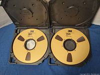 Two reels open in cases showing yellow reels and center hubs with printed media grid