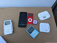 Top down view of five Apple devices and accessories placed on cardboard background.