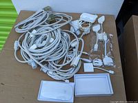 Lot of Apple power adapters, cables, USB charging cables, and adapter plugs