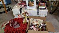 Box with Christmas decorations and cards along with red tree skirt and angel tree topper.