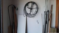 Full view of garden hooks, stakes, and wood boards stored in a corner of a garage.