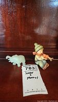 Photo shows both the jade elephant figurine and the Goebel figurine of a child playing a horn.