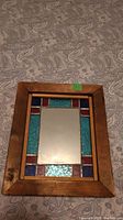 Full view of the framed stained glass mirror on patterned fabric background.