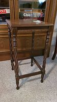 Front view of the wood occasional table showing rectangular top and ornate spindle legs.