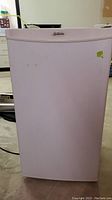 Front view of a white Sunbeam mini fridge with no visible damage and logo on the door.