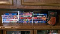 Photo of VHS tapes stacked, shows titles including Disney movies and James Bond film.