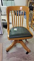 Front view of the vintage Krug wooden office chair showing curved slat backrest and green padded seat.