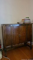 Front view of vintage wooden cabinet showing two doors with knocker style metal handles.