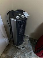 Full view of the Envion electric humidifier and heater in black and gray vertical tower design with power cord coiled around base.