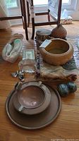 Overall group laid on hardwood floor showing bowl, statue, linens, book, bird figurines