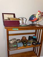 Overall view showing the Shakespeare 12-volume set on the top shelf along with rooster figurines, paint set, and various decorative boxes on lower shelves.