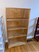 Full view of the maple wood bookshelf showing four shelves and base design.