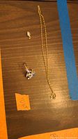 Photo shows all items: gold chain, opal pendant, and ring on wooden surface.
