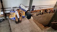 Photo of partial bags of ice melt salts, Dunhain muck boots size 8 on concrete floor in garage.