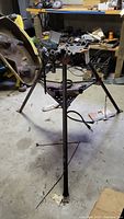 Full view of Ridgid 450 pipe stand tristand with chain vise in workshop showing three legs and chain hanging.