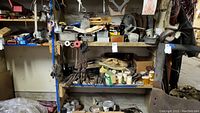 Wide view of basement shelving with assorted tools, hardware boxes, and machine parts stacked and organized loosely.