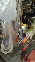 Photo showing welding electrodes in packaging on table surface with assorted aerosol cans including automotive and spray products, cord cables draped in foreground.