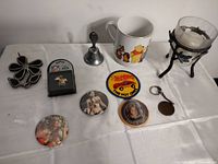 Photo of all items laid out on white surface including pins, mug, bell, candle holder, patch, and keychain
