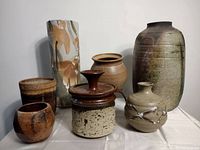 Seven pottery pieces arranged on a white surface showing shapes, colors, and finishes