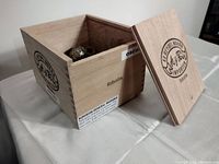 Showcases the open wooden cigar box filled with assorted jewelry pieces including rings and beads inside.