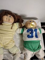 Two vintage Cabbage Patch Kids dolls shown together, showcasing overall appearance and outfits.