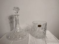 Full view of crystal decanter and ice bucket on white cloth background