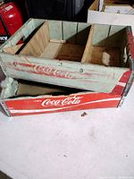 Two stacked vintage wooden Coca-Cola crates showing faded paint and internal dividers