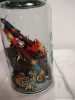 Side view of jar displaying colorful military ribbons and metal badges inside.