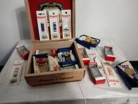 Wooden box with military medals and pins scattered around it, some boxed and some loose.