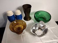 Overview photo showing all items in the lot including salt and pepper shakers, metal cup, green and amber glass bowls, and apple dish