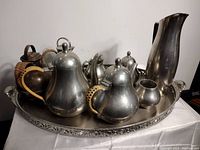 Top-front view of the full pewter tea and coffee set on the ornate tray