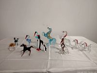 Wide angle view of assorted vintage glass figurines including horses, birds, dragons, and decorative pieces